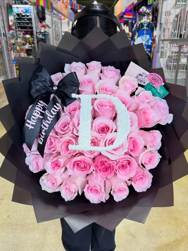 Pink roses with a pearl letter D in a black wrap