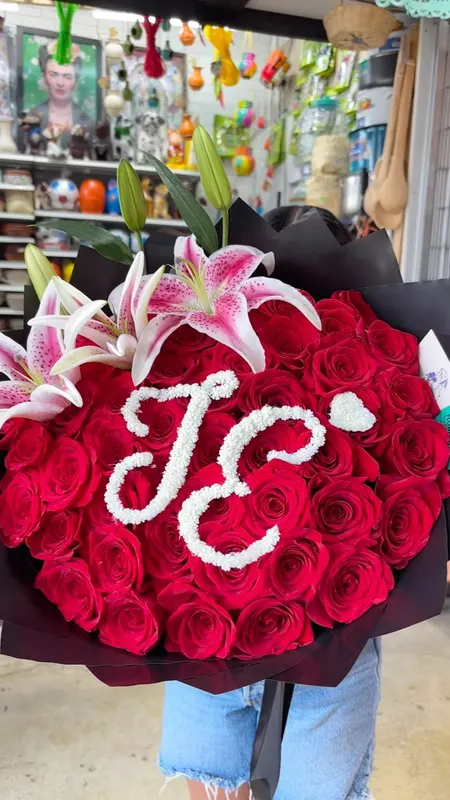 Red rose bouquet with pearl initials J and E in a black wrap