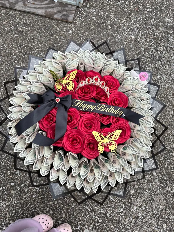 Red roses in a money-bill wrap with gold butterflies and a Happy Birthday sash
