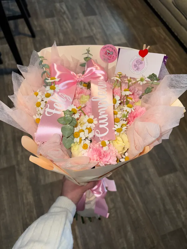 Pink bouquet with a Feliz Cumpleaños sash held in one hand