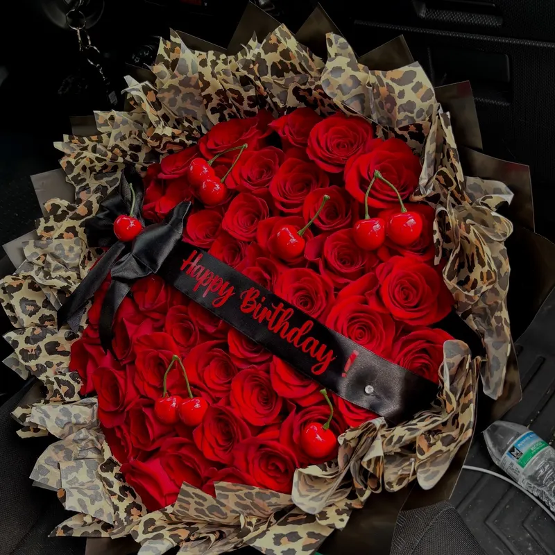 Red roses with cherries in a leopard wrap and a Happy Birthday sash